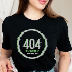 May include: A black t-shirt with a white circle containing the text "404 Gender Not Found" in green and gray text with a glitch effect.