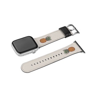 May include: A white leather Apple Watch band with a pineapple print. The band is shown attached to a silver Apple Watch.