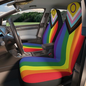 May include: Two rainbow car seat covers with a black background and a symbol of a circle with a yellow ring around it on the headrest.