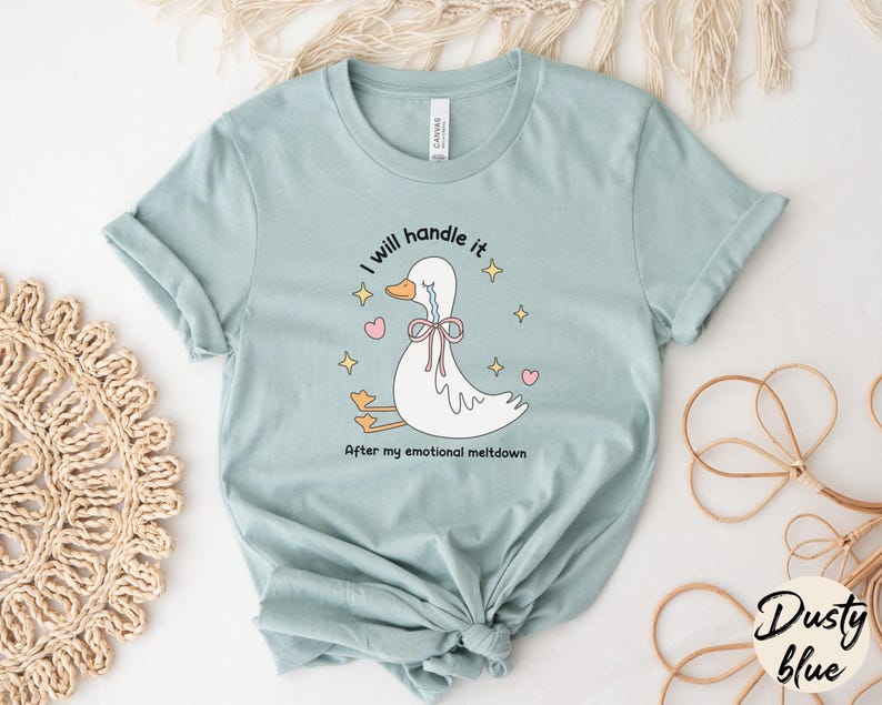 Puede incluir: Una camiseta azul claro con una ilustraci&oacute;n de un pato llorando. El texto en la camiseta dice "Lo manejar&eacute;. Despu&eacute;s de mi colapso emocional."