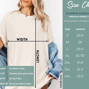 May include: Size chart for a unisex t-shirt in ivory. The chart shows the length and width measurements in inches for sizes S through 4XL. The chart also includes a guide for choosing the right size based on the desired fit.