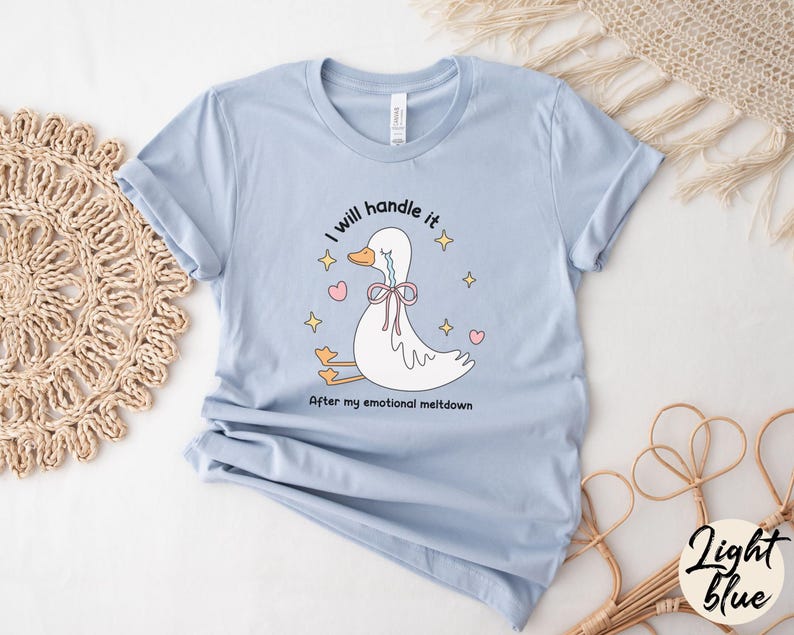 Puede incluir: Camiseta azul claro con una ilustraci&oacute;n de dibujos animados de un pato llorando. El texto de la camiseta dice "Lo manejar&eacute; despu&eacute;s de mi crisis emocional."