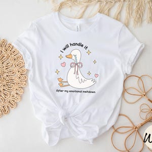 Puede incluir: Camiseta blanca con una ilustraci&oacute;n de dibujos animados de un pato llorando con el texto "Lo manejar&eacute; despu&eacute;s de mi crisis emocional."