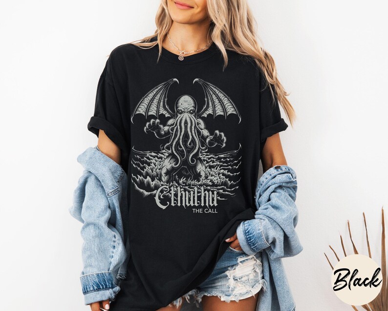 May include: Black t-shirt with a graphic print of Cthulhu, a fictional creature with tentacles and wings, rising from the sea. The text "Cthulhu The Call" is printed below the image.