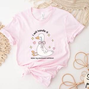 Puede incluir: Una camiseta rosa con una ilustraci&oacute;n de un pato llorando. El texto en la camiseta dice "Lo manejar&eacute; despu&eacute;s de mi crisis emocional."