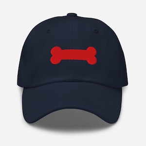 May include: A navy blue baseball cap with a red bone embroidered on the front.
