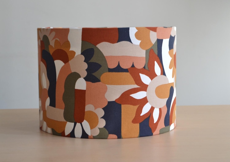 K&ouml;nnte beinhalten: Ein Lampenschirm mit einem farbenfrohen geometrischen Muster in Orange-, Braun-, Gr&uuml;n- und Blaut&ouml;nen. Das Muster zeigt abstrakte Formen und Blumen.
