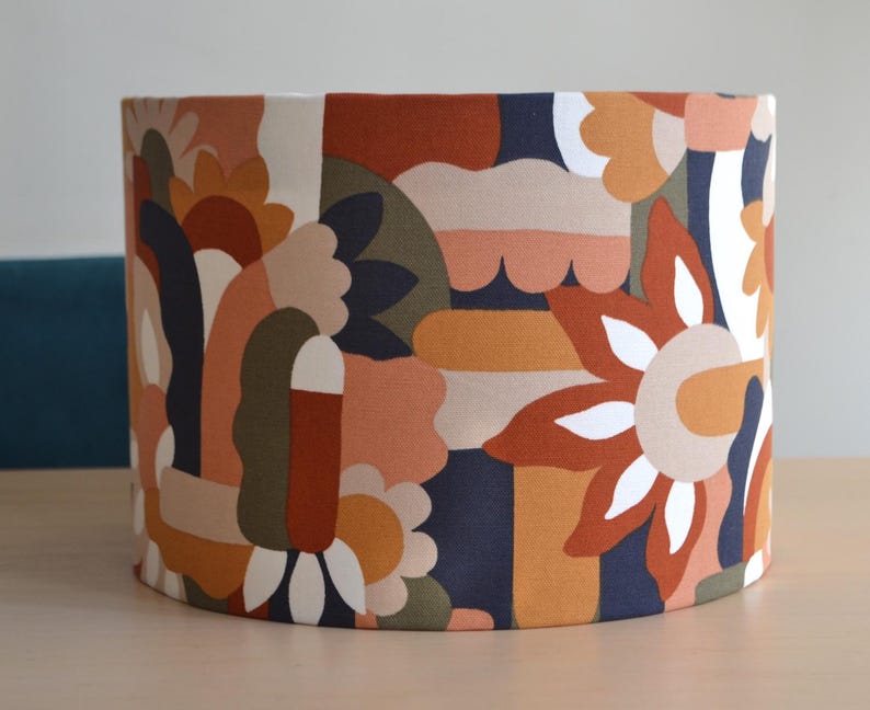 K&ouml;nnte beinhalten: Ein Lampenschirm mit einem farbenfrohen geometrischen Muster in Orange-, Braun-, Gr&uuml;n- und Blaut&ouml;nen. Das Muster zeigt abstrakte Formen und stilisierte Blumen.