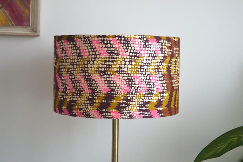 May include: A brown, gold, and pink patterned lampshade with a geometric design.