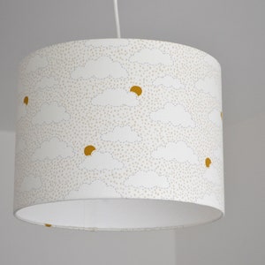 May include: A white lampshade with a pattern of small white dots and yellow suns behind white clouds.
