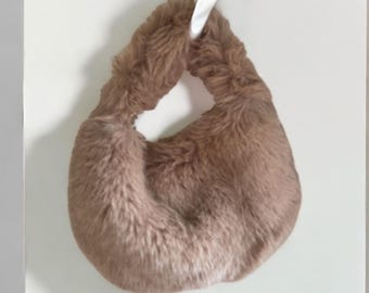 May include: A brown faux fur handbag with a single handle.