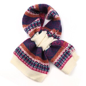 May include: A knitted scarf with a geometric pattern in cream, navy blue, burgundy, and rust colors. The scarf is folded and has a cream-colored section in the middle. The ends of the scarf are cream-colored.