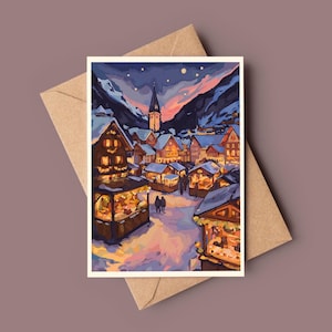 Può includere: Un biglietto di auguri raffigurante una scena di un villaggio invernale con tetti innevati, negozi illuminati e un campanile sotto un cielo crepuscolare. Il biglietto è posto su una busta marrone, suggerendo un tema festivo o stagionale.