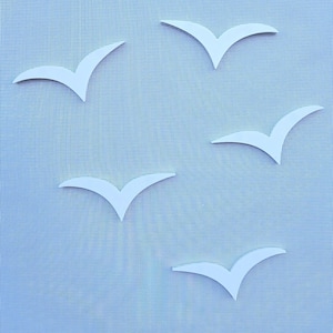 Könnte beinhalten: Fünf weiße Papier-Vögel sind ausgeschnitten und auf einem blauen, gemusterten Hintergrund platziert.