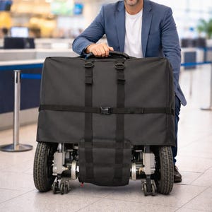 May include: A black travel mobility device with a handle, wheels, and a black cover. The device is being held by a person in a blue blazer and white shirt, in an airport setting.