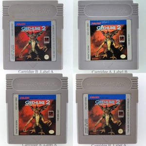 May include: Four different versions of a Game Boy cartridge for the game Gremlins 2: The New Batch. The cartridges are gray with a black label. The label features a red background with a green Gremlin character. The text on the label reads "Sunsoft Gremlins 2 The New Batch".