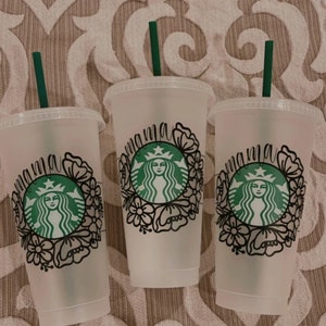 Op de afbeelding: Drie doorzichtige plastic bekers met zwarte en groene ontwerpen. Elke beker heeft een groene rietje en een zwart ontwerp dat "mama" zegt met een bloemenpatroon en een groen Starbucks-logo.