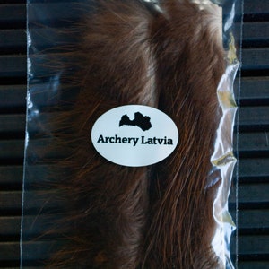 May include: Two bundles of brown fur in a clear plastic bag with a white label that says "Archery Latvia" and a black silhouette of Latvia.