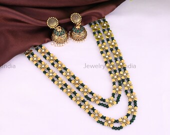 May include: A three-strand gold and green beaded necklace with flower-shaped charms. The necklace is paired with matching earrings with green stones.