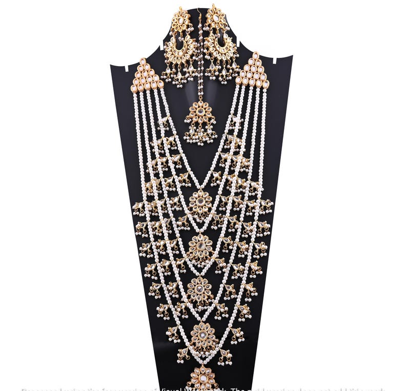 May include: A multi-strand pearl necklace with gold accents and a matching set of earrings. The necklace features multiple layers of pearls and gold embellishments, including small floral designs and mirror-like accents. The earrings are similarly adorned with pearls and gold.