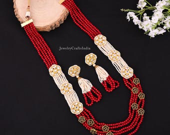 May include: A multi-strand necklace with red and white beads, gold accents, and pearl-like embellishments. Matching earrings with red and white beads and gold accents are also included.