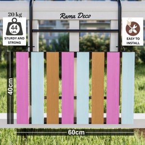 Op de afbeelding: Een houten schuttingpaneel met zes latten in de kleuren roze, lichtblauw en bruin. Het paneel is 60 cm breed en 40 cm hoog. Het paneel is gelabeld "Rama Deco" en heeft een draagvermogen van 20 kg of 44 lbs. Het paneel is gemakkelijk te installeren.