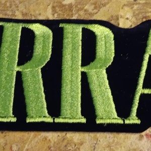 May include: Green embroidered "WARRANT" patch on a black background.