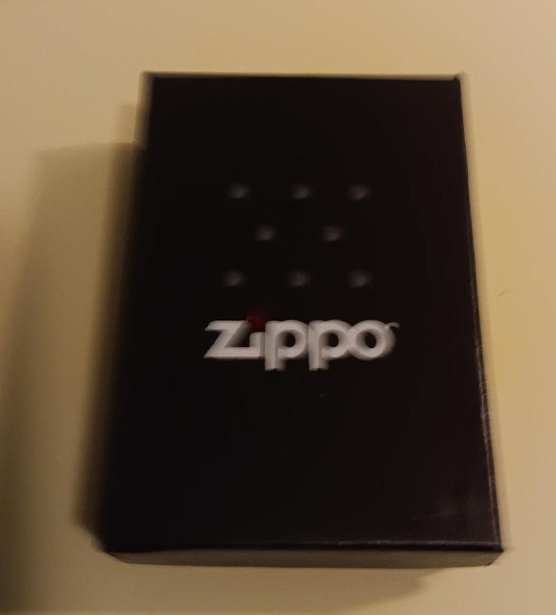 May include: Black box with the word "Zippo" in white letters on the front. The box has a pattern of small white dots.