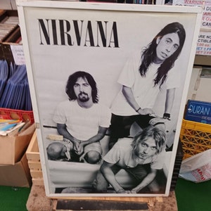 May include: Black and white photo of the band Nirvana. The band members are Kurt Cobain, Krist Novoselic, and Dave Grohl. The photo is from a magazine or poster.