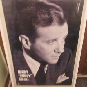 May include: Black and white framed portrait of Benny "Bugsy" Siegel. The image shows a man in a suit and tie, with a white pocket square. The text "Benny "Bugsy" Siegel" is printed at the bottom of the frame.