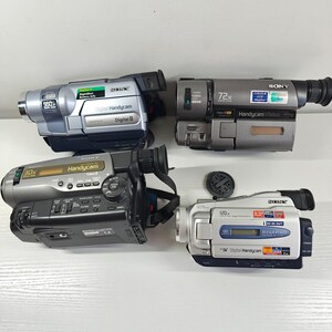 May include: Four Sony Handycam camcorders in various shades of grey and silver. The devices feature labels including Digital 8, Video 8, 560x, 72x, 30x, and 120x digital zoom, along with various buttons, viewfinders, and lens caps visible on the units.