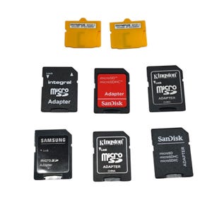 May include: A collection of memory card adapters from brands such as Kingston and SanDisk. The adapters are in black, red, and yellow, with text detailing their type and brand. Some feature a lock mechanism.