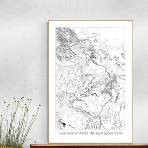 May include: A black and white map of the Continental Divide National Scenic Trail. The trail is shown as a thick black line winding through the mountains. The map is framed in a white frame.