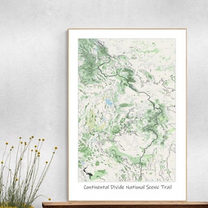 May include: A framed map print of the Continental Divide National Scenic Trail, featuring a detailed topographical view in shades of green and white. The print is in a wooden frame and includes the trail's name at the bottom.