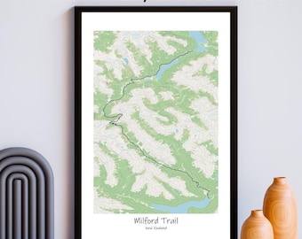 May include: A framed print of a topographic map of the Milford Trail in New Zealand. The trail is highlighted in black, and the surrounding landscape is shown in shades of green and blue.