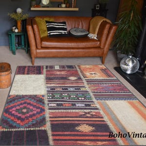 Puede incluir: Una alfombra de patchwork multicolor con un patrón geométrico. La alfombra está en una sala de estar con un sofá de cuero marrón, un sillón verde y una chimenea.