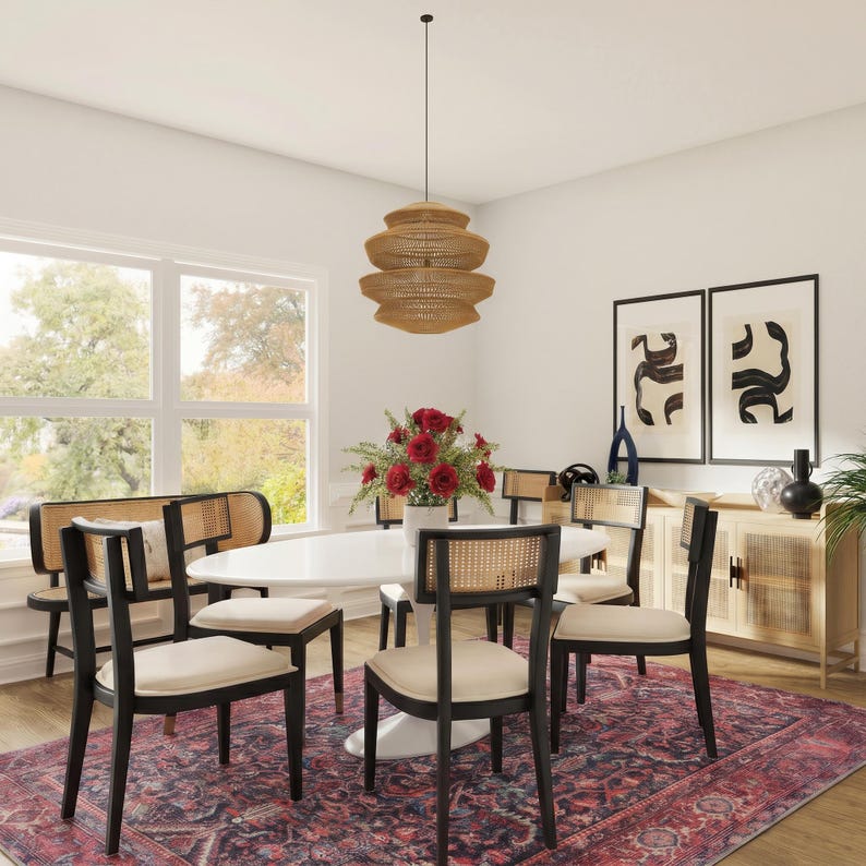 May include: A dining room set featuring a white oval table, four black chairs with cane backrests and cream cushions, and a matching bench. A tiered woven pendant light hangs above, while a sideboard and a patterned rug complete the space.