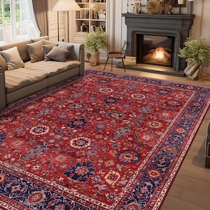 Puede incluir: Una alfombra rectangular grande con un fondo rojo intenso y patrones florales y geométricos intrincados en tonos azul marino, crema y azul claro. La alfombra tiene un borde ancho de color azul oscuro con motivos ornamentados repetidos.