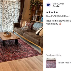 May include: A rectangular area rug featuring a dark red and navy blue intricate pattern with a decorative border. The rug measures 5 feet by 7.5 feet and is positioned on a light wood floor beneath a wooden coffee table and two brown sofas.