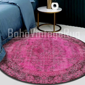 Puede incluir: Una alfombra redonda de color rosa y negro con un patrón floral. La alfombra tiene un aspecto desgastado y es perfecta para añadir un toque de estilo bohemio a cualquier habitación.