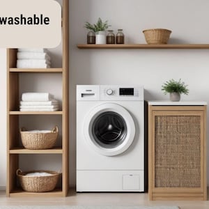 May include: A modern laundry room with a white washing machine, wooden shelving, and a woven cabinet. The shelves hold white towels and wicker baskets. The text "Machine washable" is displayed.