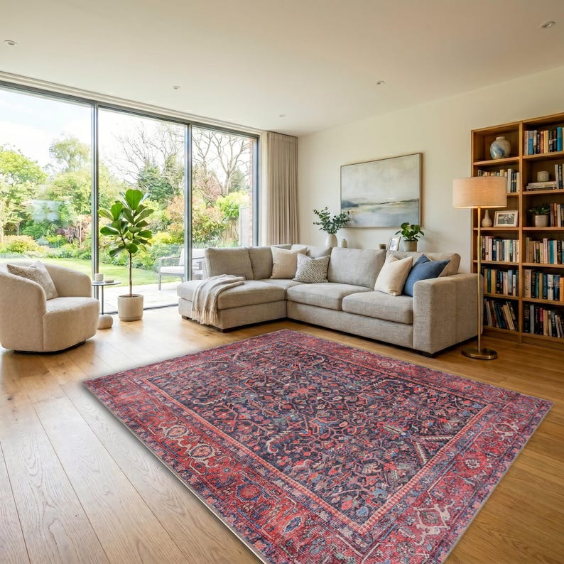 May include: A rectangular area rug featuring a dark navy blue center with intricate floral and vine patterns in shades of red, pink, and cream, surrounded by a wide, ornate border in deep red with matching floral motifs and geometric details.