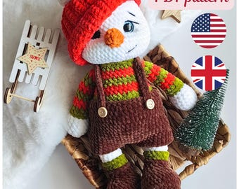 May include: A handmade crochet snowman doll wearing a red hat, striped sweater, and brown overalls. The snowman has a carrot nose and button eyes. A small wooden sled and a miniature Christmas tree are nearby. The text "PDF pattern" is visible.