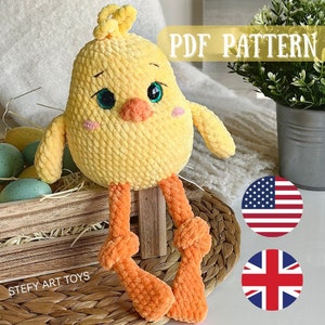 Puede incluir: Un juguete de pollito amarillo tejido a crochet con patas naranjas y un pico. El pollito está sentado en una cesta tejida con una base de madera. La imagen incluye el texto "PDF PATTERN" y "STEFY ART TOYS".