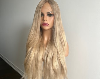 Op de afbeelding: Een lange, rechte, lichtblonde pruik met een natuurlijke scheiding. De pruik is gestyled met zachte golven en wordt gedragen op een mannequinhoofd.