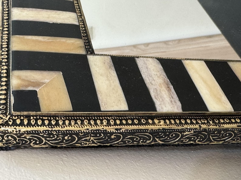 Detailed close-up of the bone inlay texture and ornate gold brass trim surrounding the mirror edge moroccan mirror.