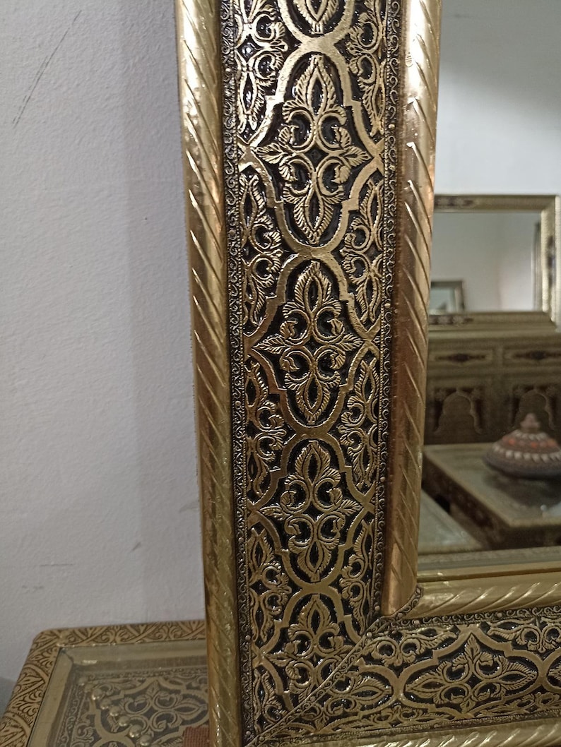Intricate hand-carved detail on a large Moroccan etched brass wall mirror, showing traditional gold metalwork and Arabesque motifs for a unique bohemian entryway or living room styling