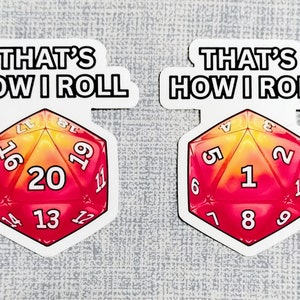 May include: Two stickers with the text "THAT'S HOW I ROLL" and a red and yellow dice with a 20 and a 1 on them.