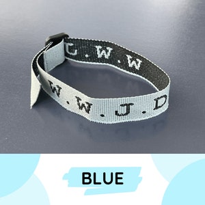 Pode incluir: Uma pulseira tecida branca e preta com o texto "C.W.W.W.J.D." impresso nela. A pulseira é azul.