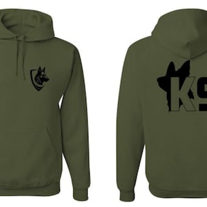 Könnte beinhalten: Ein grüner Kapuzenpullover mit einer schwarzen Silhouette eines Deutschen Schäferhundes und dem Text "K9" auf der Rückseite. Die Vorderseite des Pullovers zeigt eine schwarze Silhouette eines Deutschen Schäferhundekopfes in einem Schild.